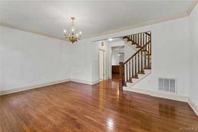 Empty room with dark wood-type flooring, an inviting chandelier, and crown molding