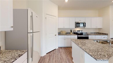 Kitchen featuring sink, white cabinets, light hardwood / wood-style floors, stainless steel appliances, and light stone countertops