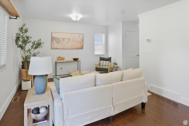 Living area with dark wood-type flooring and ornamental molding