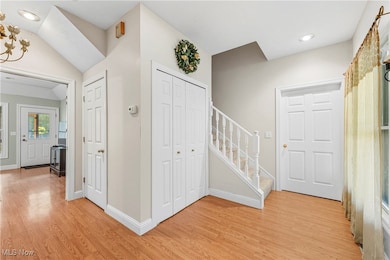 Entrance foyer featuring recessed lighting, light wood-style floors, stairway, and vaulted ceiling
