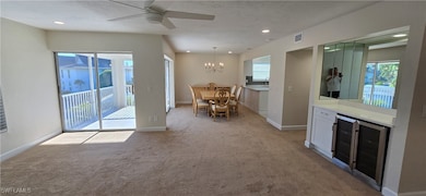 Living room with light carpet, plenty of natural light, a ceiling fan, a chandelier, and recessed lighting