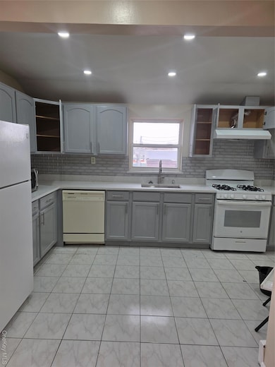 Kitchen with gray cabinets, stove, refrigerator, dishwashing machine, and recessed lighting