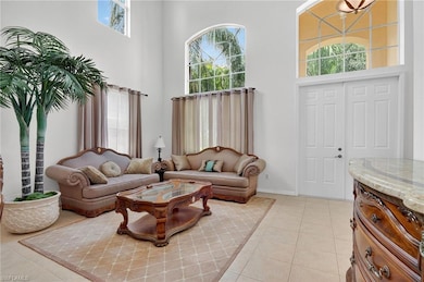 Living area with healthy amount of natural light, a towering ceiling, and light tile patterned flooring