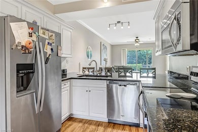 Kitchen with ceiling fan, light wood-type flooring, rail lighting, white cabinets, and appliances with stainless steel finishes