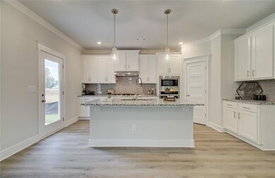 Kitchen with a sink, appliances with stainless steel finishes, under cabinet range hood, white cabinets, and decorative backsplash