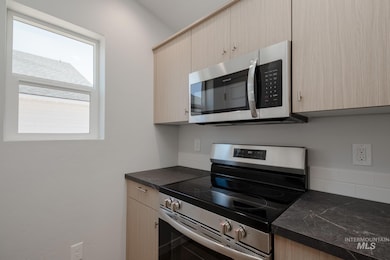 Kitchen with stainless steel appliances, dark countertops, and light brown cabinets