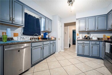 Kitchen with a sink, a textured ceiling, appliance