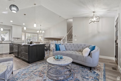 Living area with a chandelier, vaulted ceiling, stairs, light wood-type flooring, and recessed lighting