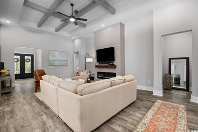 Living area with coffered ceiling, wood finished floors, a ceiling fan, a towering ceiling, and recessed lighting