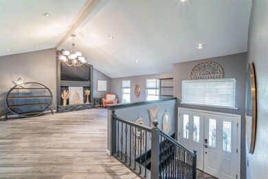Hall featuring a notable chandelier, lofted ceiling with beams, light hardwood / wood-style floors, and a healthy amount of sunlight