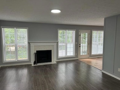 Unfurnished living room with a tiled fireplace, wo