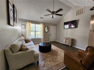 Living room featuring visible vents, vaulted ceili