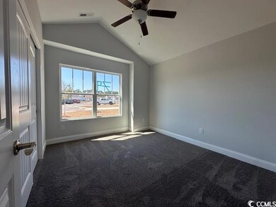 Empty room featuring lofted ceiling, visible vents, dark carpet, ceiling fan, and baseboards
