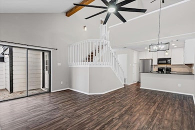 Unfurnished living room with high vaulted ceiling, dark wood finished floors, beamed ceiling, stairway, and ceiling fan