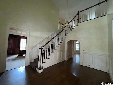 Staircase featuring a decorative wall, wood finished floors, arched walkways, plenty of natural light, and a high ceiling