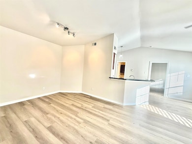 Unfurnished living room featuring vaulted ceiling and light wood-style floors