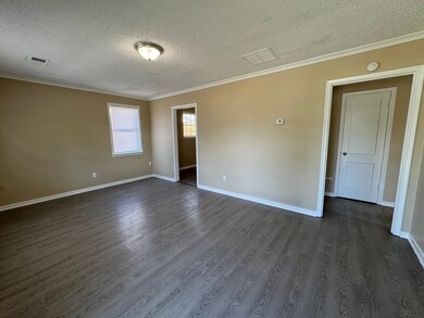 Empty room featuring crown molding, dark wood-type