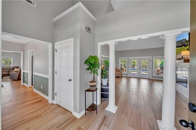 Foyer entrance featuring visible vents, light wood finished floors, ornate columns, and a healthy amount of sunlight