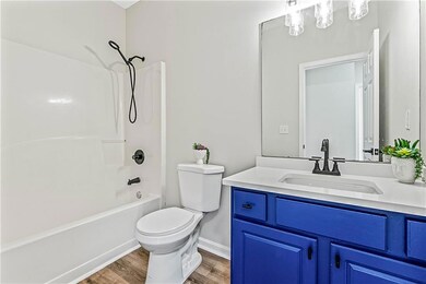 Bathroom featuring washtub / shower combination, vanity, and dark wood-style floors