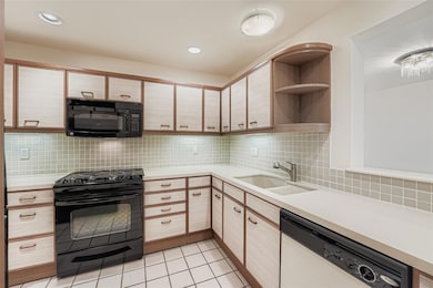 Kitchen featuring black appliances, open shelves,