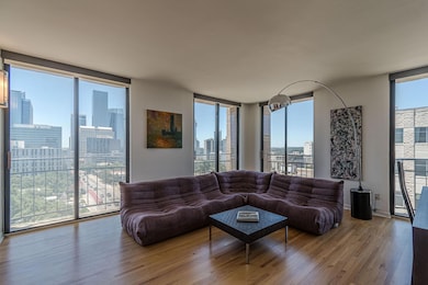 Living area with wood finished floors, healthy amount of natural light, floor to ceiling windows, and a skyline view