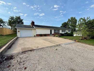 Ranch-style home featuring concrete driveway, a chimney, and an attached garage