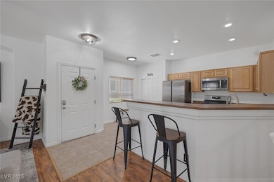 Kitchen with appliances with stainless steel finishes, a kitchen bar, a peninsula, dark countertops, and recessed lighting