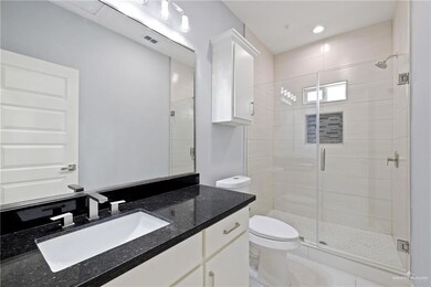 Bathroom with a stall shower, vanity, and recessed lighting
