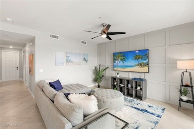 Living room featuring light tile patterned floors, a decorative wall, and a ceiling fan