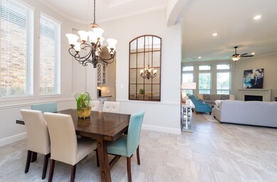 The dining room features a coffered ceiling with a graceful chandelier and crown molding, chair railing and a doorway to the butler's pantry for ease in serving your guests.