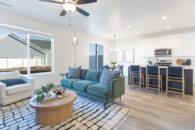 Living area featuring light wood-style flooring, recessed lighting, a chandelier, and ceiling fan