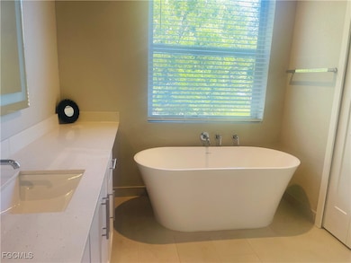 Full bathroom with vanity, a freestanding tub, and light tile patterned floors