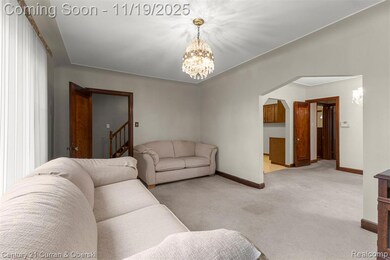 Carpeted living room featuring a chandelier, arched walkways, and stairway