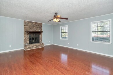 Unfurnished living room with hardwood / wood-style floors, ceiling fan, a brick fireplace, and plenty of natural light