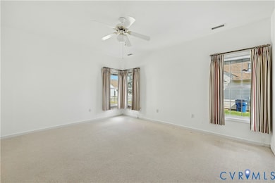 Empty room with carpet flooring, healthy amount of natural light, and a ceiling fan