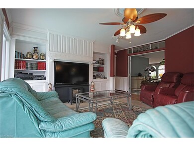 Living room with entertainment center, large windows over looking the pool. French doors separate formal dinning room.