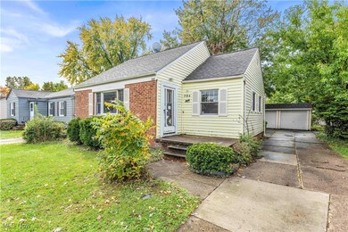 Bungalow with a front yard, a garage, and an outbuilding