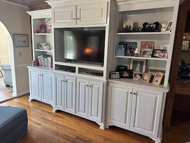 Detailed view of arched walkways, wood finished floors, crown molding, and built in features