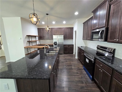 Kitchen featuring stainless steel appliances, a sink, tasteful backsplash, ornamental molding, and dark brown cabinetry