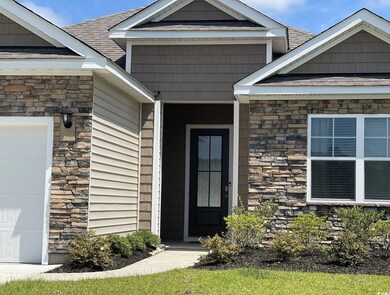 Entrance to property with stone siding, roof with shingles, and a garage