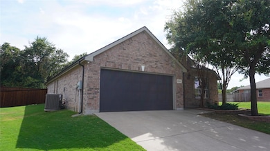 View of front of home with a garage, a front yard, and central AC unit