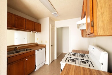 Kitchen featuring white appliances, a sink, under