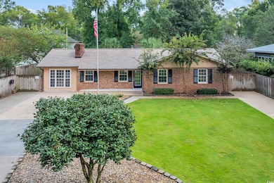 Ranch-style home with a chimney, brick siding, roof with shingles, and driveway