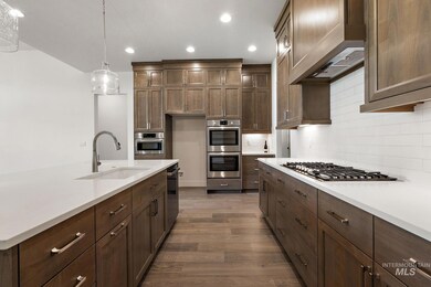 Kitchen with appliances with stainless steel finishes, dark wood-style flooring, tasteful backsplash, light countertops, and recessed lighting