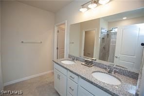 Full bath with baseboards and double vanity