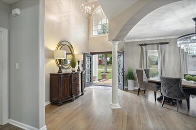 Foyer with an inviting chandelier, plenty of natural light, ornate columns, and light wood-type flooring