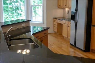 Kitchen - dark countertops, light wood-style flooring, and tasteful backsplash