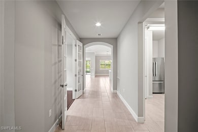 Corridor with arched walkways, baseboards, and rec