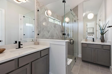 Bathroom with a stall shower, two vanities, and light tile patterned flooring