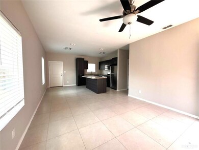 Kitchen featuring freestanding refrigerator, open floor plan, a center island, light countertops, and light tile patterned floors